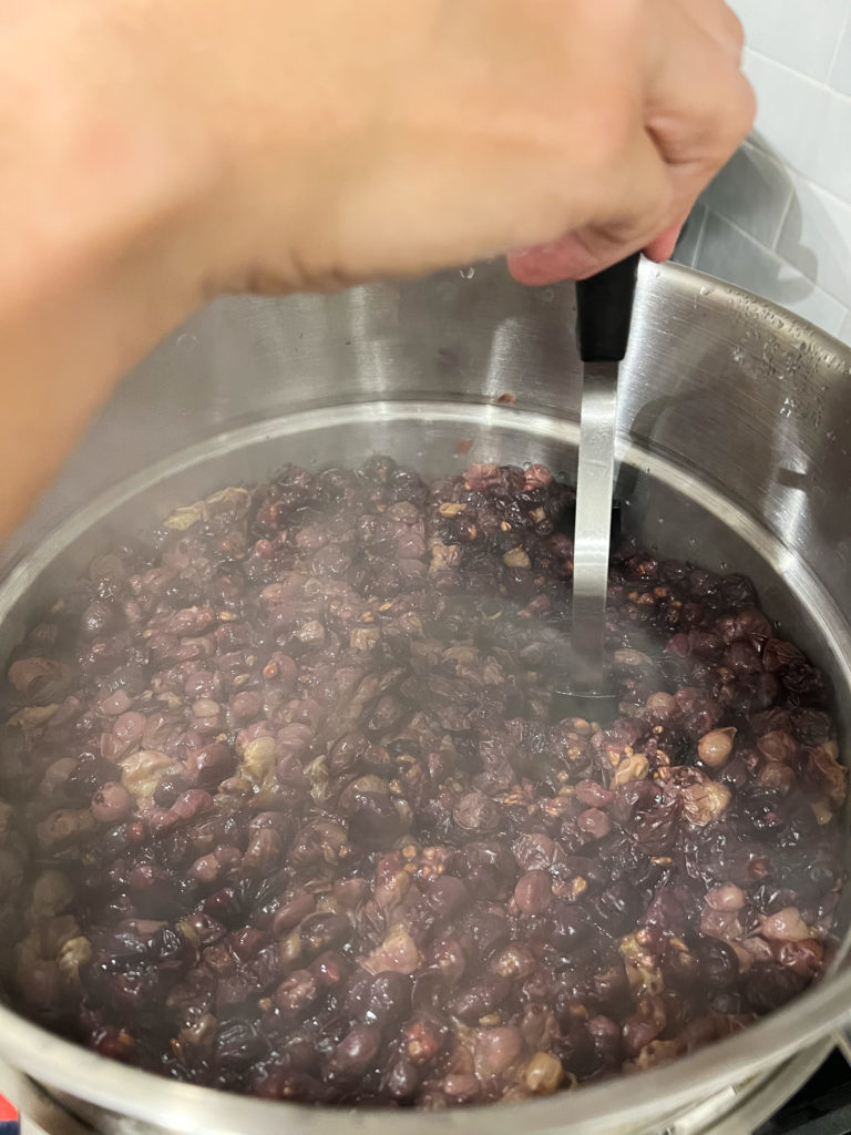 mashing grapes to make homemade grape juice